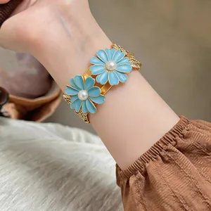 Detailed view of an elegant blue enamel daisy cuff bracelet featuring pearl centers