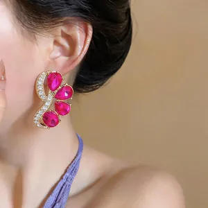 Close-up of elegant oversized earrings with pink teardrop gemstones on model