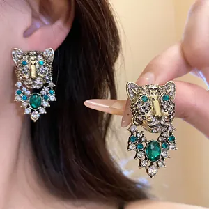 Close-up of vintage leopard head earrings featuring green and clear rhinestones detail.