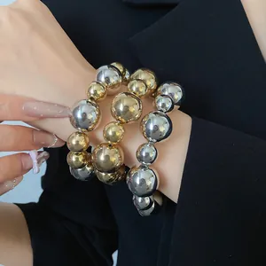 Close-up of three-piece smooth metallic gold and silver beaded bracelet on wrist