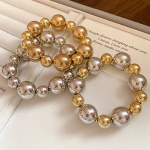 Close-up of three geometric shiny gold and silver bead bracelets on a jewelry tray