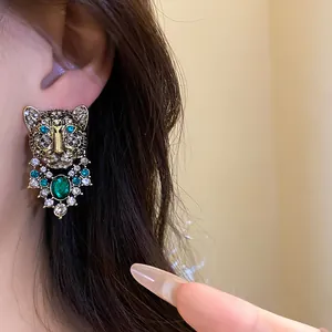 Detailed view of vintage leopard stud earrings with green rhinestones and gold finish