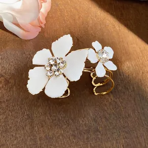 Close-up view of a gold-plated cuff bracelet featuring white daisy flowers with crystals.