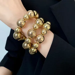 Close-up detail of three-piece vintage gold beaded bracelet set on wrist with black blazer