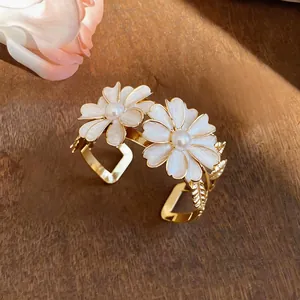 Detailed close-up view of a golden daisy cuff bracelet with white petals and pearls