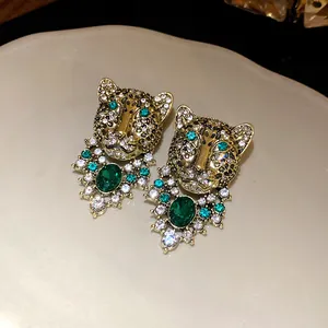 Close-up detail of vintage leopard head earrings with green crystals and rhinestones