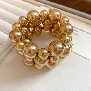 Close-up detail of golden smooth spherical beaded bracelet with reflective finish