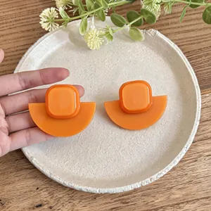 Vue détaillée de boucles d'oreilles géométriques en acrylique orange sur une assiette
