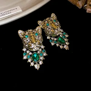 Macro view of vintage gold leopard earrings with emerald rhinestones