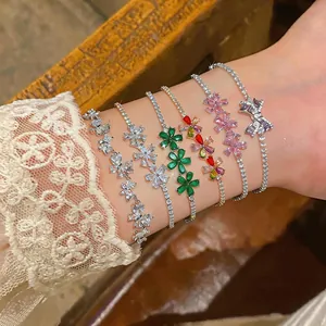 Detail of sparkling zircon bracelets with floral and bow designs on a wrist.