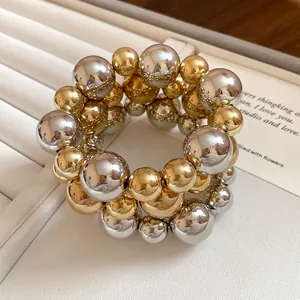 Close-up of 3-piece gold and silver metallic beaded bracelets set on a white tray
