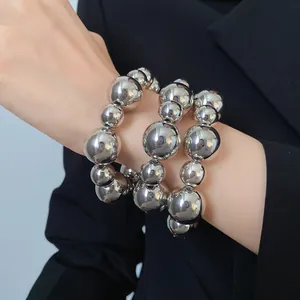 Macro view of three-piece silver metallic bead bracelets set worn on a model's wrist