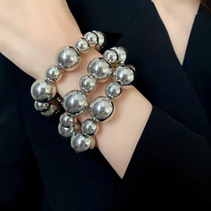 Macro view of chunky silver metallic beaded bracelet set worn by a female model
