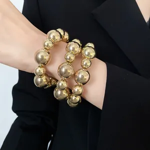 Close-up of a retro chunky gold beaded bracelet set for women worn with a black blazer