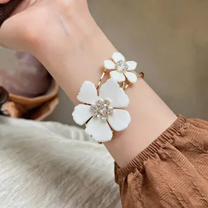 Close-up view of a large white daisy floral bangle with sparkling crystal centers on wrist