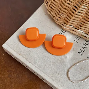 Gros plan détaillé de boucles d'oreilles géométriques en acrylique orange sur livre