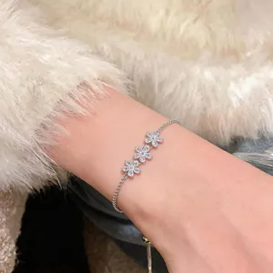 Detailed view of silver-tone flower bracelet with sparkling zircons on a wrist.