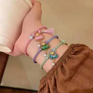 Close-up of handmade braided bracelets with cute embroidered dumpling charms and tassels