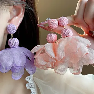 Macro detail of handmade raffia and purple chiffon flower drop earrings for beach vacation
