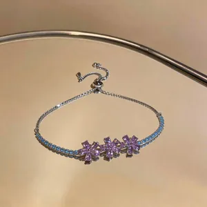 Close-up of elegant 18K gold plated bracelet with pink zircon flowers and blue crystals