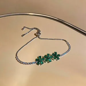 Macro view of luxurious 18k gold-plated bracelet featuring green zircon flower charms