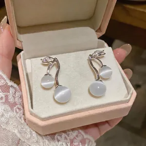 Elegant silver needle earrings with white cat's eye stones and zircon in a pink box