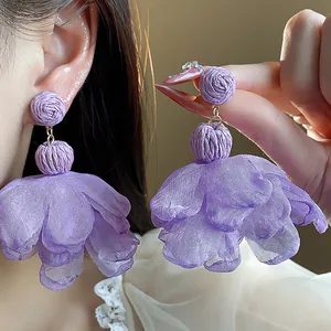 Close-up detail of lavender purple chiffon flower earrings with raffia craft design