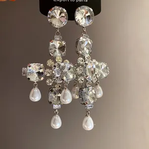 Detailansicht eleganter Kreuzohrringe mit glänzenden Kristallen und Tropfenperlen