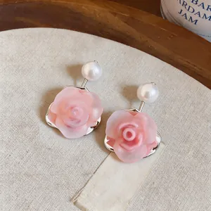 Macro detail shot of sweet pink resin rose flower earrings with elegant white pearls