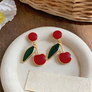 Vintage enamel cherry drop earrings with a high-end minimalist design on a white plate