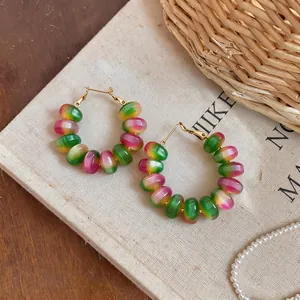 Close-up of macaron gradient beaded hoop earrings on minimalist canvas background