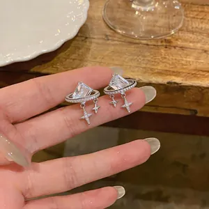 Macro detail of planet-shaped earrings with square-cut crystal and dangling star charms