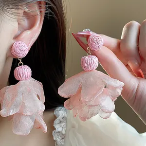 Detailed macro view of pink raffia and layered chiffon flower drop earrings for women