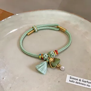 Close-up detail of hand-woven bracelet featuring a cute green Zongzi charm and tassel