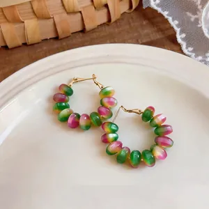 Macro view of colorful macaron gradient beaded hoop earrings resting on a white ceramic plate