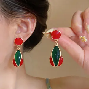 Detailed close-up of vintage red and green enamel cherry-style drop earrings on model