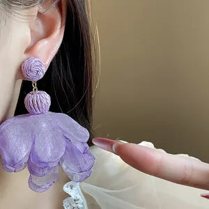 Macro detail of elegant purple raffia and chiffon layered flower earrings on ear