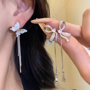 Close-up of asymmetrical butterfly and bow tassel earrings with sparkling stones