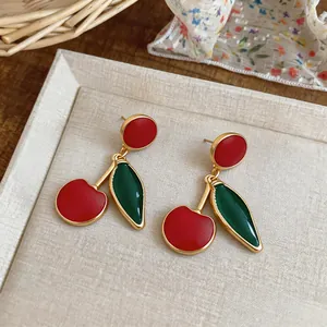 Macro view of vintage style enamel cherry earrings featuring red and green charms