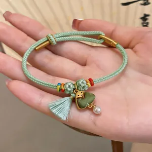 Detail of a handmade green woven bracelet with zongzi charm and pearl for festival