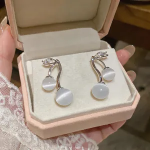 Detail of elegant cat-eye stone earrings with zircon accents in a pink gift box.
