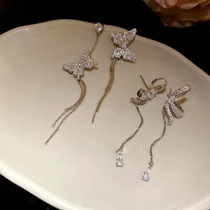 Macro view of elegant silver butterfly and bow tassel earrings with sparkling crystals