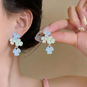 Close-up of pastel blue and green floral dangle earrings with sparkling rhinestone accents