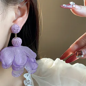 Macro view of purple chiffon flower earrings with raffia beads for a holiday look.
