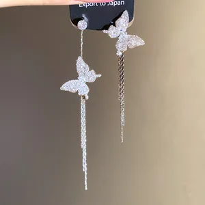 Detailed close-up of asymmetrical butterfly tassel earrings with sparkling stones