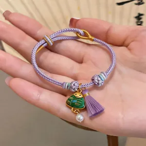 Close-up of a hand-woven purple bracelet with a cute Zongzi charm and tassel detail