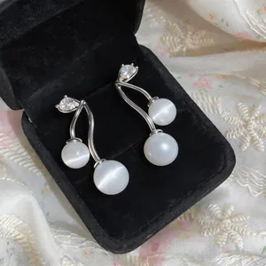 Close-up of elegant cat's eye earrings with zircon accents in black velvet box