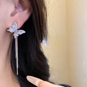 Detailed close-up of sparkling butterfly earrings with long chain tassels worn on ear.