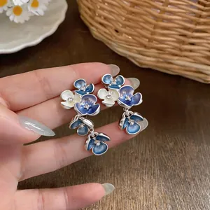 Detailed view of blue and white enamel floral cluster earrings featuring central crystals