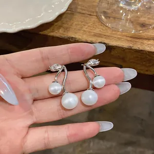 Detailed view of silver cherry earrings featuring white cat's eye stones and zircon